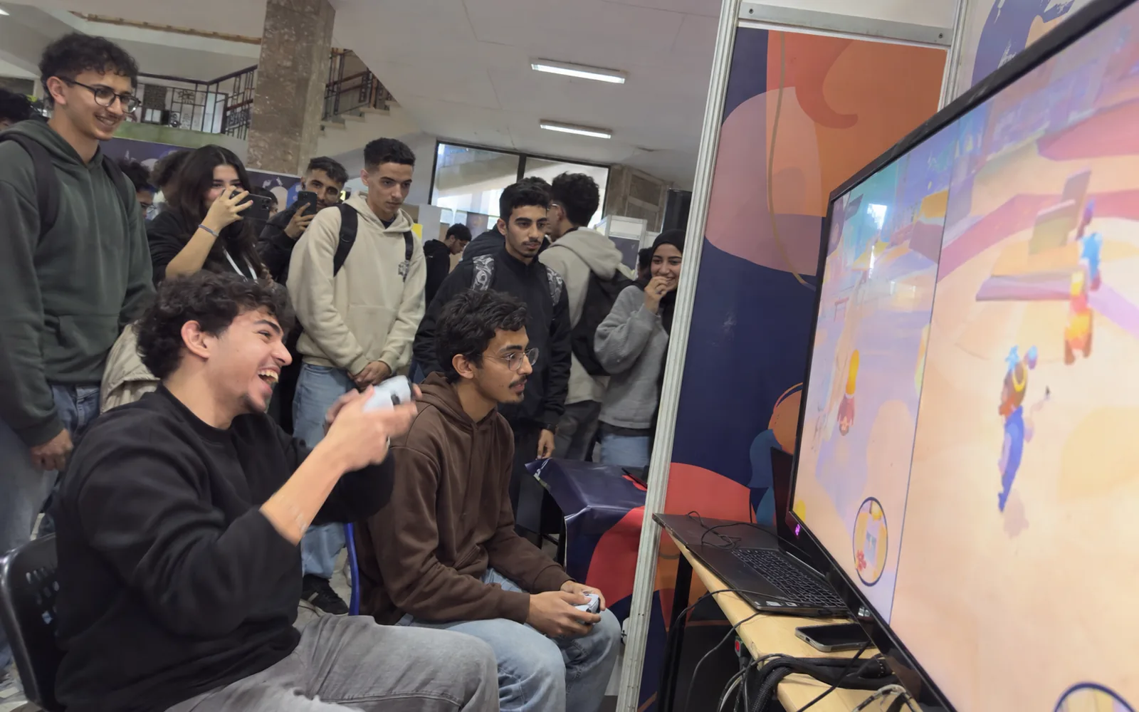Deux étudiants s’affrontent sur un jeu de marque lors d’un événement gaming, devant un public qui filme